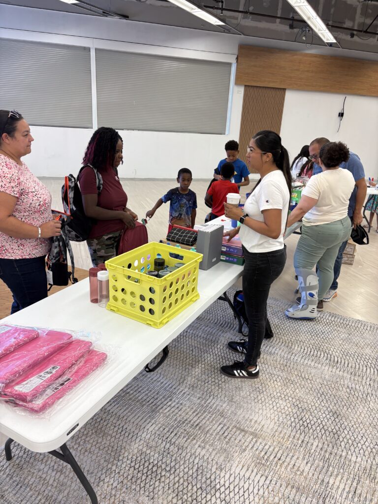Adults speaking with Silvia, the marketing director, about the organization's mission and activities during an event in Boise, Idaho.